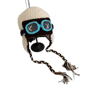 Hand-knitted aviator-style beanie with earflaps and colorful braided tassels in off-white
