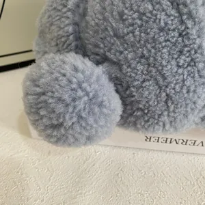 Nahaufnahme der hellblauen Teddy-Fleece-Textur und des Plüsch-Pompons auf der Kappe