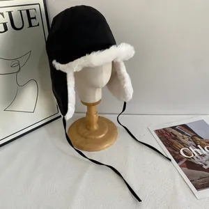 Close-up of black windproof winter trapper hat with white plush lining and chin straps