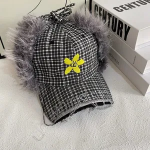 Detail of plaid earflap hat with faux fur lining and yellow flower embroidery
