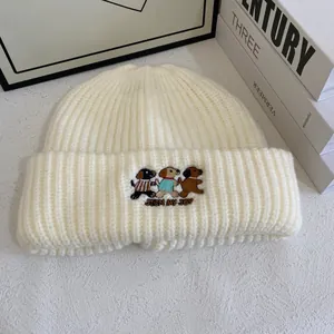 Detail of cute dog embroidery and Join My Joy text on cream knit winter beanie