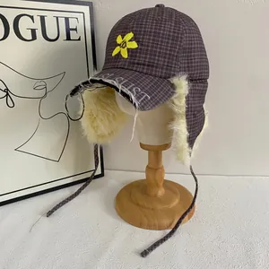 Detail of purple plaid pilot hat with plush lining and yellow flower embroidery