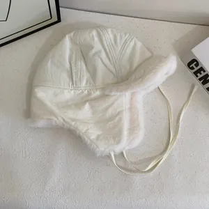 Close-up of a creamy white fleece-lined trapper hat with windproof shell and ear flaps