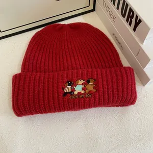 Macro detail of red ribbed knit beanie featuring cute puppy embroidery and text