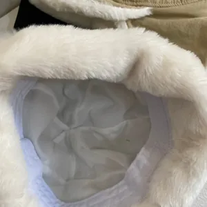Detail of white plush trapper hat showing soft faux fur texture and warm inner lining