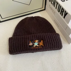 Close-up of deep brown chunky knit beanie with cute puppy embroidery and JION MY JOY text