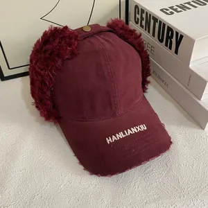 Detailed close-up of dark red trapper baseball cap with plush earflaps and embroidery