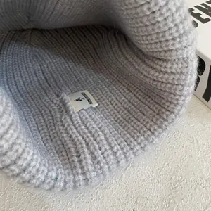Close-up of the soft knit texture and woven inner label of the grey beanie