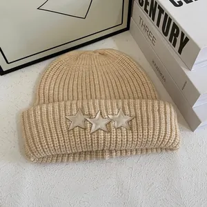 Gorro de punto grueso beige con parches de estrellas y textura de lana cálida