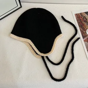 Flachbild einer schwarzen Strickmütze mit Ohrenklappen, Kontrastrand und Bindebändern