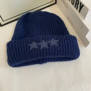 Detalle de cerca del gorro de punto azul marino con parches de estrellas y lana gruesa