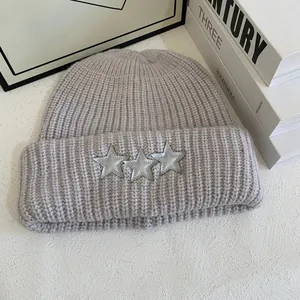 Detalle del gorro de punto lila con parches de estrellas y textura de canalé grueso