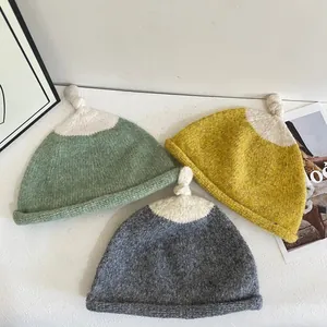 Chic color-block knitted beanies in sage green, mustard, and grey with top knots