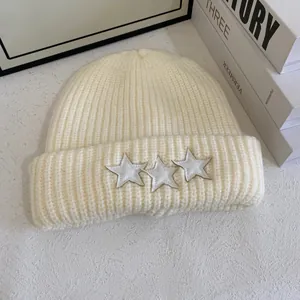 Detalle del gorro de punto acanalado crema con parches de estrellas y borde doblado