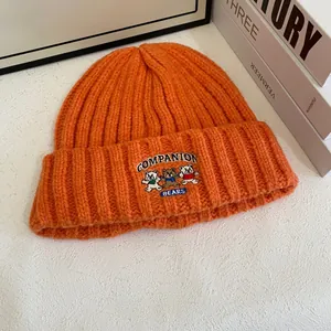 Detalle del gorro naranja con bordado de tres osos y texto de Companion Bears