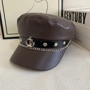 Detail of dark brown leather newsboy cap with silver anchor charm and metal chain