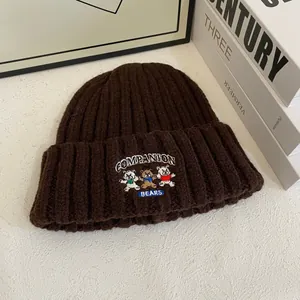 Primer plano detallado del gorro de punto marrón oscuro con bordado de tres ositos
