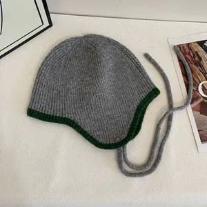 Detailansicht der dunkelgrauen Strickmütze mit waldgrüner Paspelierung und langen Bindebändern