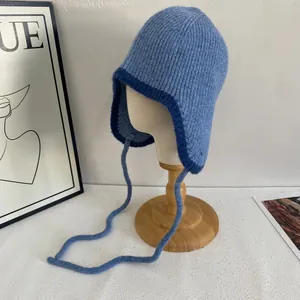 Detail der blauen Strickmütze mit Ohrenklappen und Bindebändern auf einem Schaufensterpuppenkopf