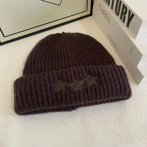 Detalle de la textura del gorro de punto marrón oscuro con parches de estrellas de cuero