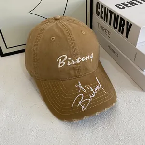 Close-up of khaki cotton baseball cap with white embroidery and distressed brim details