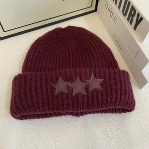 Primer plano del gorro de punto granate con tres parches de estrellas y textura gruesa