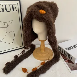 Detail van pluche wintermuts met zacht materiaal en opvallende oranje pluizige bollen