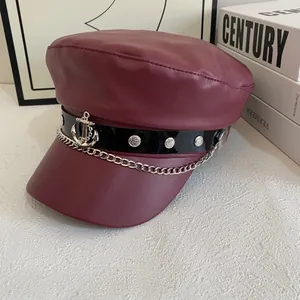 Detail of burgundy PU leather baker boy hat featuring silver anchor charm and chain links