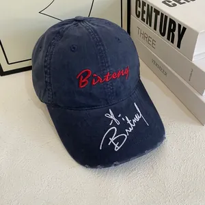 Close-up of distressed navy baseball cap with red embroidery and white brim signature