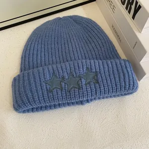 Detalle del gorro de punto grueso azul marino con tres parches de estrellas en el dobladillo