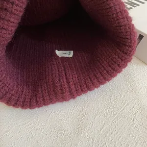 Primer plano del gorro de punto acanalado burdeos que muestra el tejido y la etiqueta interna
