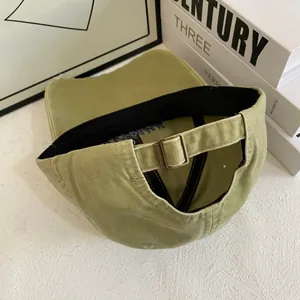 Detail of washed green cotton baseball cap showing metal buckle and inner sweatband