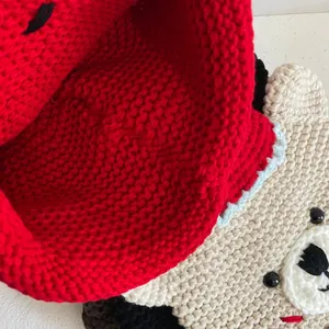 Detailed macro shot of handmade red and cream knit hat featuring cute animal face design