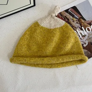 Detailed top view of a chunky two-tone knit beanie with stylish top knot decoration
