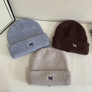 Three distressed knit beanies with puppy embroidery in blue, brown and beige colors
