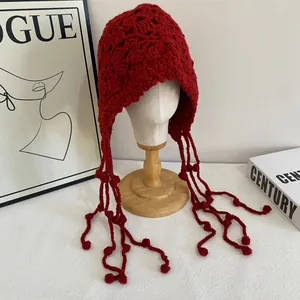 Détail du bonnet péruvien rouge en tricot fait main avec cache-oreilles et pompons longs