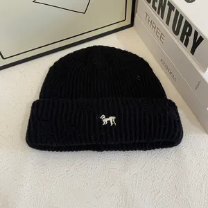 Close-up of black ribbed knit beanie featuring detailed white puppy embroidery and thick texture