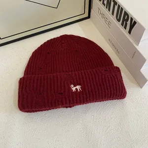 Distressed dark red knit beanie with white animal embroidery and a warm thick texture