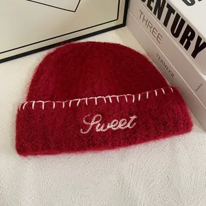 Detail of red mohair knit beanie featuring white Sweet letter embroidery and stitch trim