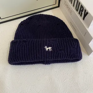 Detail of navy blue ribbed beanie featuring white dog embroidery and trendy distressed holes