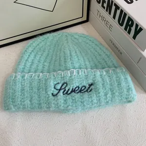 Detailed texture of mint green knit beanie featuring Sweet embroidery and rolled edge