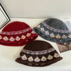 Winter vintage jacquard knit bucket hats in red, grey, and brown on a minimalist table