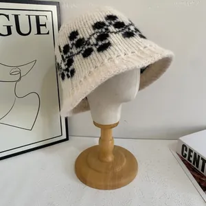 Dettaglio del cappello bucket in maglia beige vintage con motivi floreali neri e texture soffice