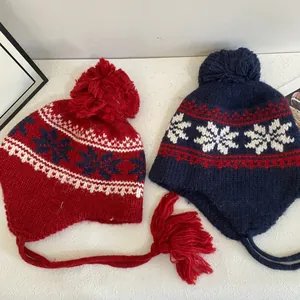 Fair Isle knit hats with pom-poms and earflaps in red and navy blue snowflake patterns