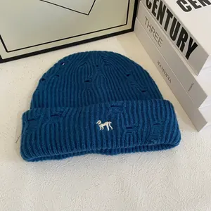 Detailed knit texture of blue distressed beanie with white animal embroidery detail