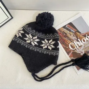 Detailed knit of Nordic snowflake pattern on ear-flap hat with warm plush pom-pom