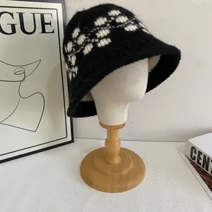 Dettaglio cappello a secchiello in maglia geometrica bianco e nero su supporto legno