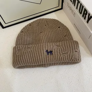 Detailed macro view of brown distressed knit beanie with blue puppy embroidery detail