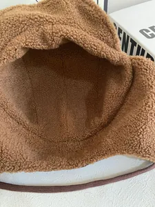 Detailopname van dikke bruine sherpa fleece textuur en trekkoord op winterse pilotenmuts