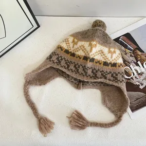 Dettaglio cappello in maglia Fair Isle con paraorecchie, nappe e pompon di peluche